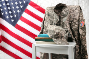 Military uniform and books laid upon table and chair with U.S flag in background