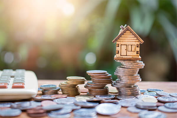 Miniature home sitting on pile of cash