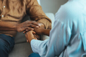 Caregiver caring for a veteran who is sitting on a couch