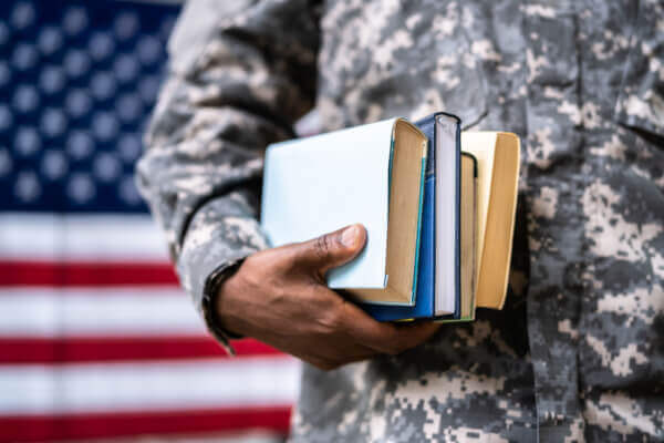 Military member holding a stack of books