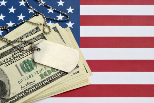 Stack of cash with dog tags and American flag