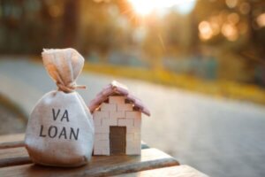 Bag of money labeled VA Loan next to model of a home