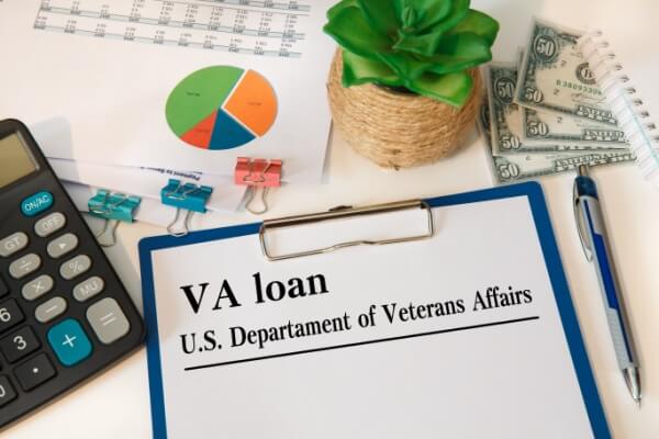 Paper with VA loan on the table, calculator and glasses.