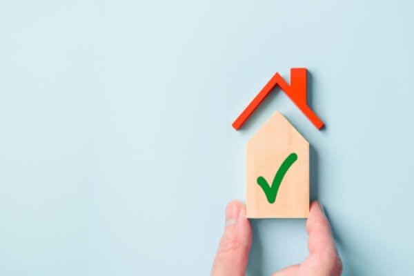 VA Mortgage loan approved small wooden house check box mark on a blue background.