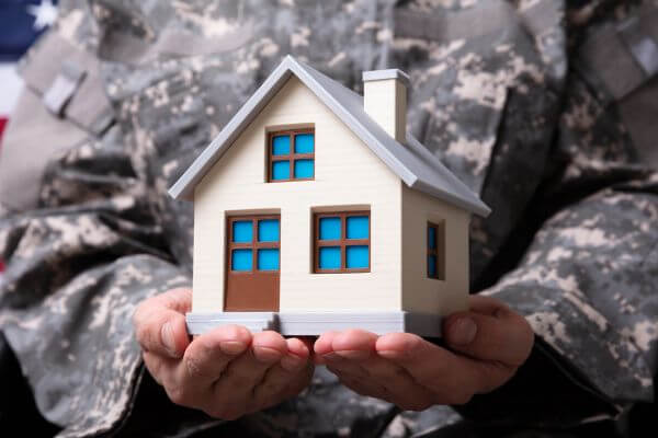 Solider Holding Model House In Hand.